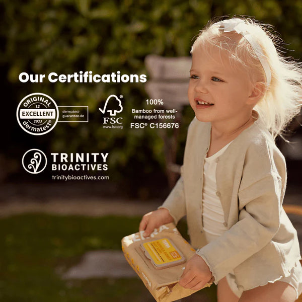 Child holding a product with certifications displayed on a blurred natural background