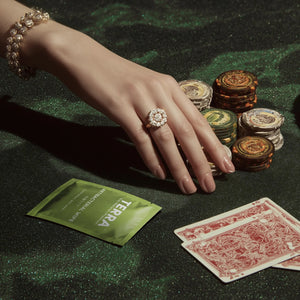 Hand with a ring on a poker table with chips and cards, featuring Terra Antibacterial Wipes.