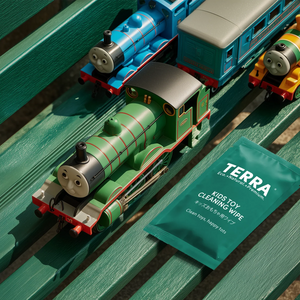 Toy trains on tracks with a TERRA cleaning wipe packet in the foreground